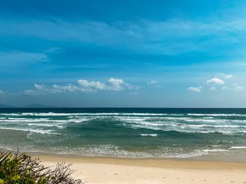 Sandy seashore, calm soft waves at sea, sunny weather, blue sky with white cl Stock Photos