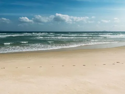 Sandy seashore, calm soft waves at sea, sunny weather, blue sky with white cl Stock Photos