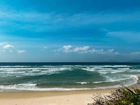 Sandy seashore, calm soft waves at sea, sunny weather, blue sky with white cl Stock Photos