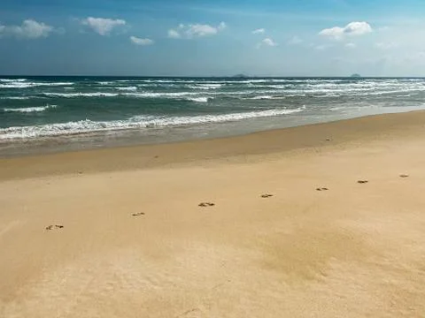 Sandy seashore, calm soft waves at sea, sunny weather, blue sky with white cl Stock Photos