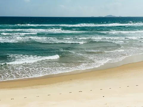 Sandy seashore, calm soft waves at sea, sunny weather, blue sky, white clouds Stock Photos