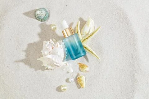 Sandy setting highlights a serum bottle adorned with sea shells. Ready for .. Stock Photos