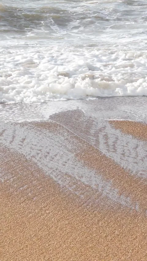 Sandy shore receiving soft waves lapping, creating serene oceanfront landscape 库存影片 308877583