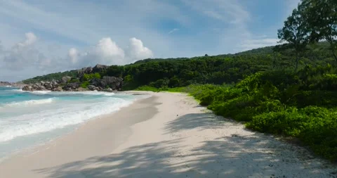 Sandy shoreline with turquoise waves and footprints. La Digue, Seychelles. 스톡 동영상 345382808