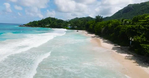 Sandy shoreline with turquoise waves and dense green vegetation. Seychelles 스톡 동영상 345384562