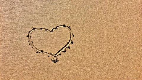 A sandy surface with a distinct heart shape etched into it. Foto stock