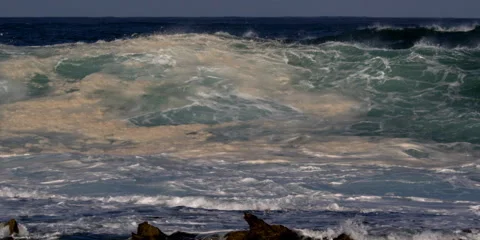 A sandy wave churning and exploding above a rocky reef Stock Footage 59525405