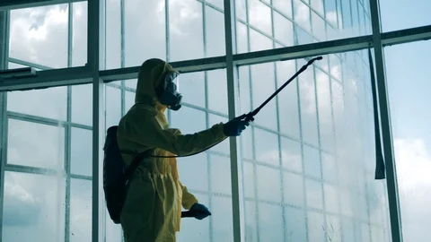 Sanitary expert is disinfecting a massive window Stock Footage 129515904