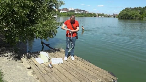 Sanitary service officer testing river water quality during hot summer heatwave. Stock Footage 342118307