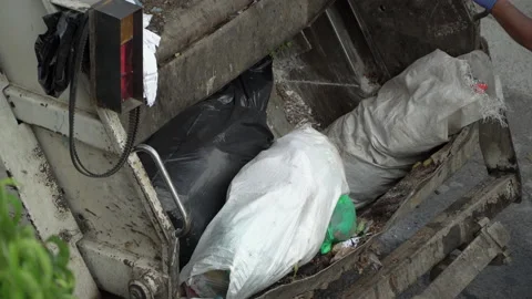 Sanitation Worker dumps a trash can into a garbage truck Stock Footage 231647568