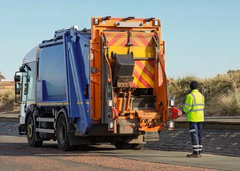 Sanitation worker operating refuse collection truck during waste pickup Fotos Stock