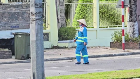 Sanitation worker wearing conical hat and blue uniform with reflective strips Stock Footage 326378730