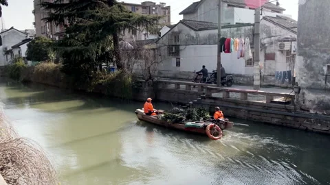 Sanitation workers in orange high-visibility jackets navigate a small motorized Stock Footage 341634142