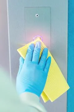 Sanitizing an elevator push button against bacteria and virus. Stockfoto's