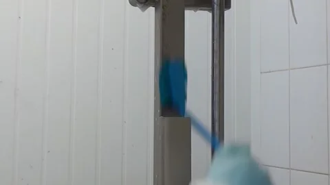 Sanitizing Industrial Machine With Blue Brush Inside a Facility During the Day Stock Footage 321416587