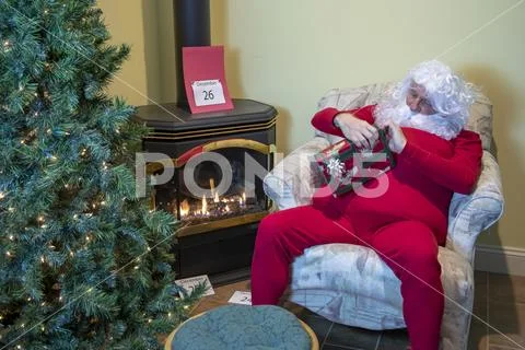 Sant unwrapping gift after Christmas Stock Photos
