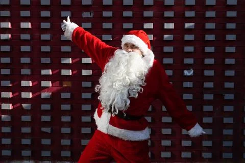 Santa Claus in the dancing pose in front of a red and white wall Stock Photos