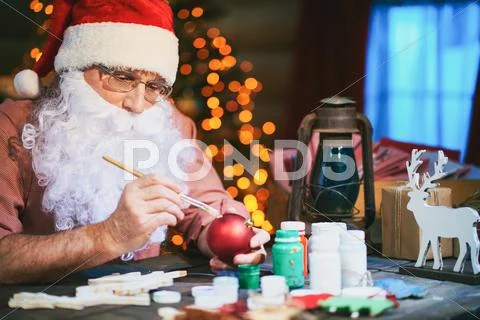 Santa Claus decorating Christmas baubles at the table Stock Photos