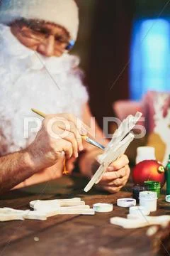 Santa Claus decorating wooden deer Stock Photos