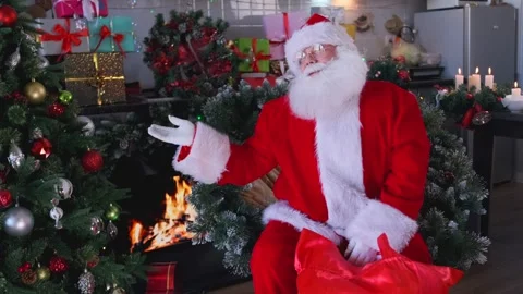 Santa Claus digging through a bag of gifts and pointing at an empty space Stock Footage 290897852