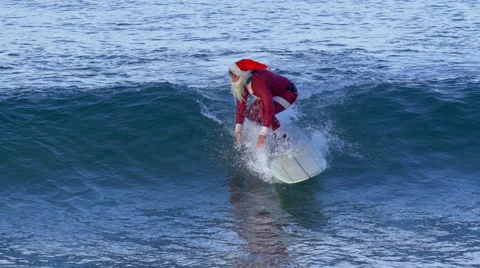 Santa Claus does a hang five trick while riding a wave surfing. Stock Footage 68025947