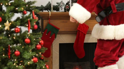 Santa Claus fills Christmas stockings with gifts Stock Footage