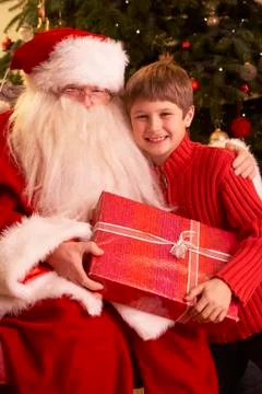 Santa Claus Giving Gift To Boy In Front Of Christmas Tree Stock Photos