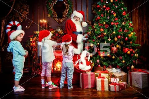 Santa Claus is giving presents to children at home. Merry Christmas and Happy Stock Photos