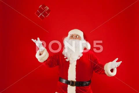 Santa Claus gloved hand with giftbox, on a red background. Christmas Stock Photos