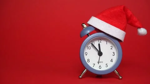Santa Claus hat on a Clock in red background. Clock ticking showing twelve hours Stock Footage 315412987