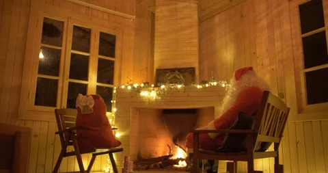 Santa Claus having a rest in a comfortable chair near the fireplace at home. Stock-Footage 125121513