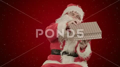 Santa Claus holding a gift in his hand on red background with snow Stock Photos
