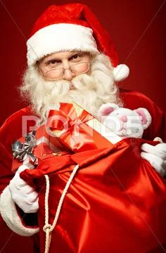 Santa Claus holding sack of gift boxes and looking at camera Stock Photos