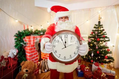 Santa Claus holding a watch in his hand, pointing at the clock at five minute Stock Photos