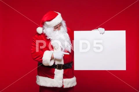 Santa Claus pointing in blank advertisement banner isolated on red background Stock Photos