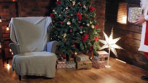 Santa Claus puts a gift under the tree Stock Footage 84004541