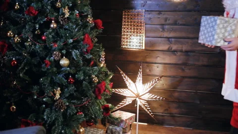 Santa Claus puts a gift under the tree Stock Footage 86234560