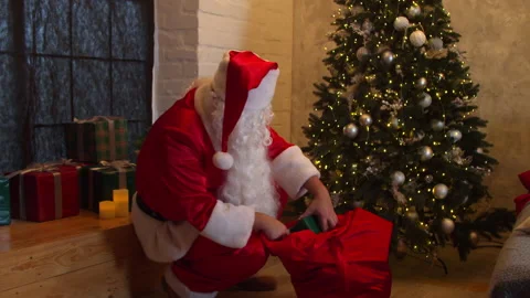 Santa Claus putting gift boxes under Christmas tree Video stock 142686415