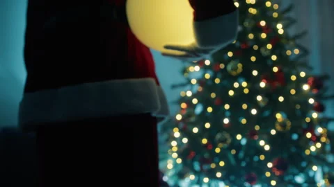 Santa claus putting a light ball under the Christmas tree Stock Footage 257206443
