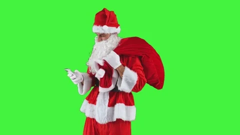 Santa Claus sending text messages with his smartphone while holding a sack .. Stock Footage 285348258