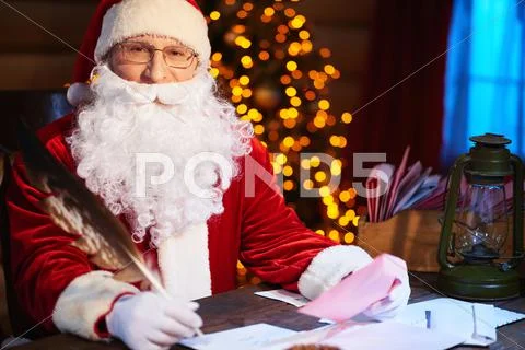 Santa Claus sitting at the table and writing letters Stock Photos