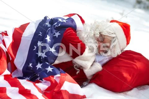 Santa claus sleeping under american flag in winter forest Stock-Fotos