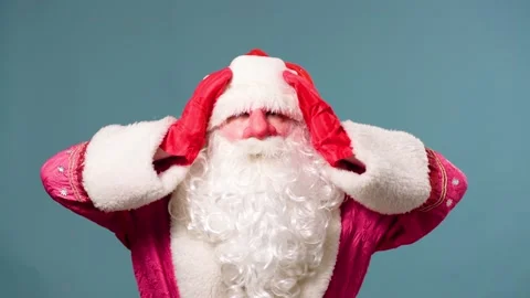 Santa Claus stands on a blue background, put his hands on his head, red gloves Stock Footage 211680976