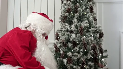 Santa Claus taking presents out of his bag uner the Christmas tree Vídeo Stock 71010901