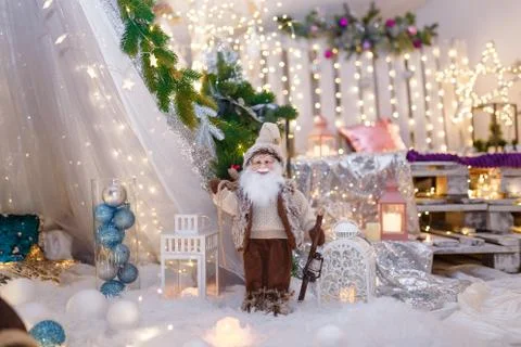 Santa Claus toy dressed in brown standing at white decorative lantern. Stock Photos