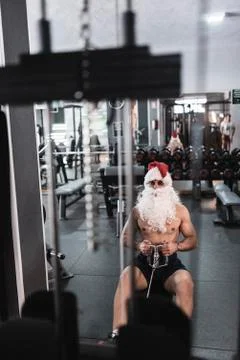Santa claus training in rowing machine after christmas holidays reducing his  Stock Photos