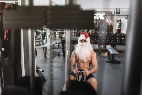 Santa claus training in rowing machine after christmas holidays reducing his  Stock Photos