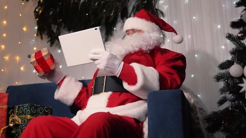Santa Claus uses tablet computer, checking his childrens gift list. Modern Stock Footage 317342105