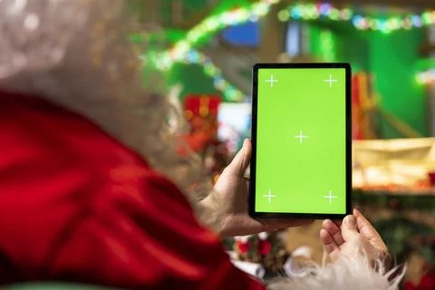 Santa Claus using mockup tablet in festive workshop to read letters from kids Stock Photos