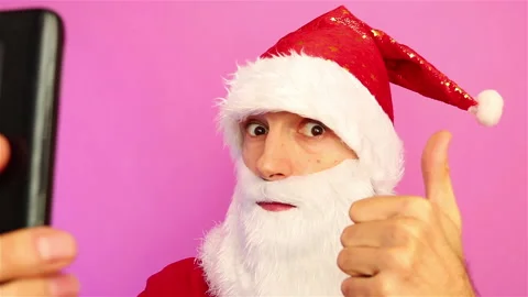 Santa claus using smartphone and pointing finger on it showing thumb up Stock Footage 143125820